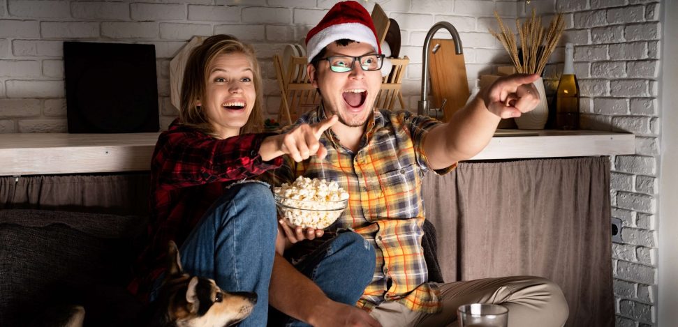 Weihnachtsfilme musst du dir ansehen! Junges Paar sieht sich einen Weihnachtsfilm an.